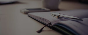 Image of a pen resting on a diary next to a phone and a mug. This is the header image for the news page and blog for Law of the Jungle.